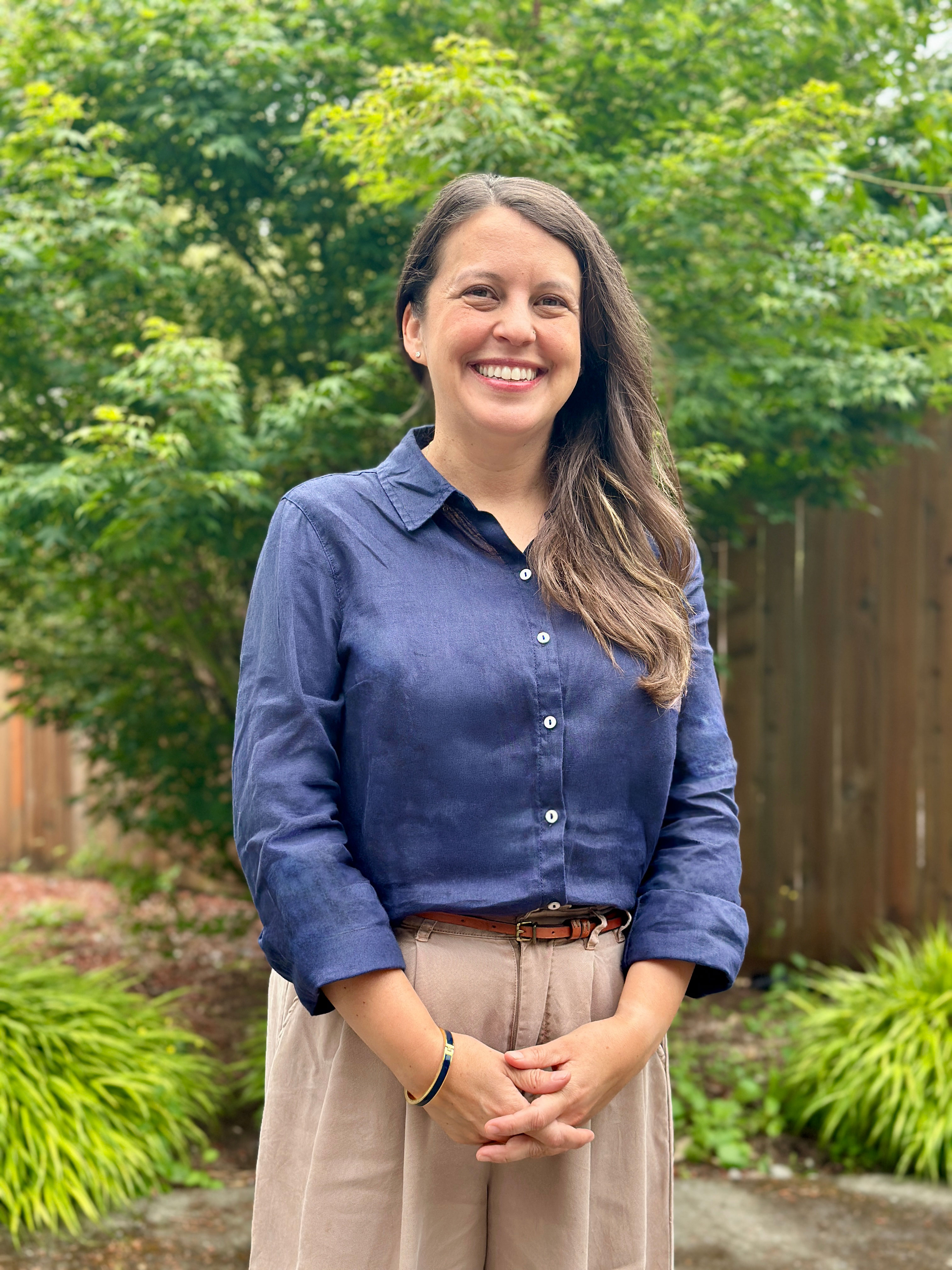 Yvonne Ontiveros, LICSW — therapist at Little Moments Therapy, smiling outdoors against a backdrop of Seattle greenery